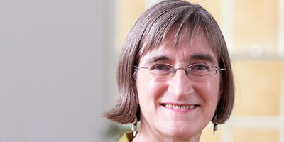 Woman wearing glasses and smiling at camera.